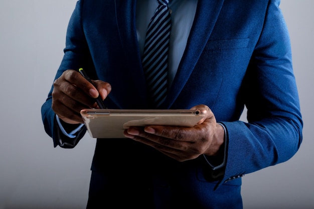 Sección intermedia del empresario utilizando tableta gráfica contra el fondo gris
