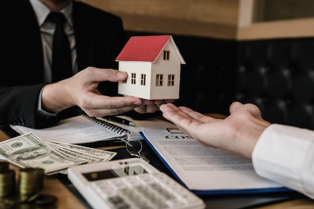 Sección media de un agente inmobiliario con un cliente que tiene una casa modelo en la oficina