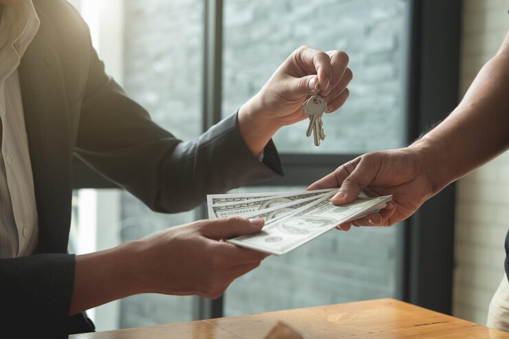 Foto sección media del agente inmobiliario dando llaves al cliente mientras recibe monedas de papel en la oficina