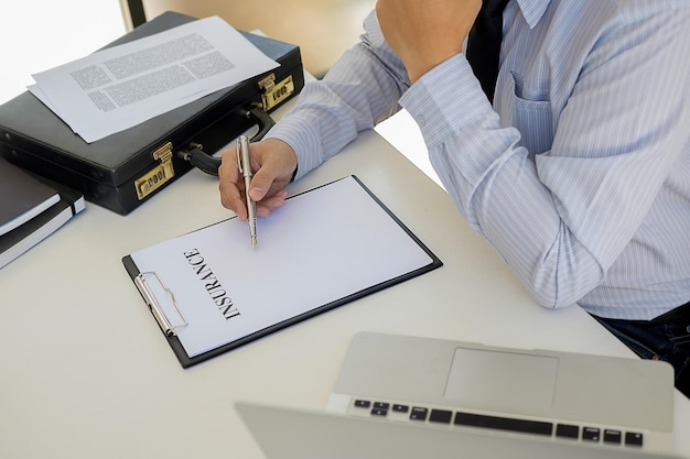 Foto sección media del agente de seguros escribiendo en el formulario en la oficina