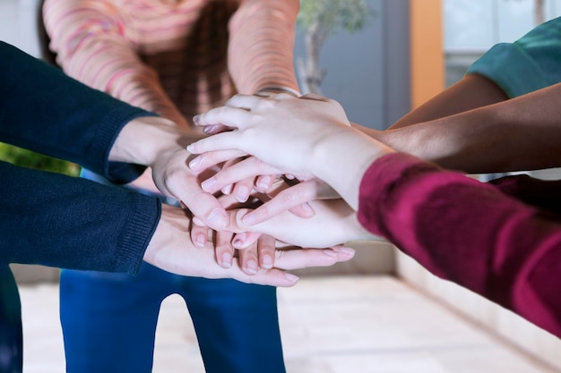 Foto sección media de amigos apilando las manos en casa