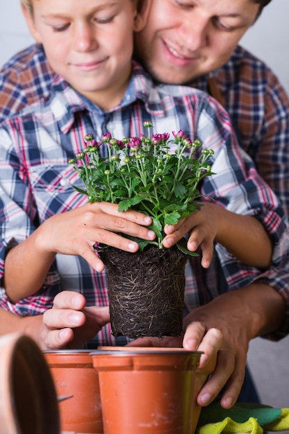 Sección media de amigos sosteniendo una planta en maceta