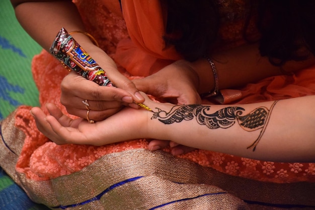 Sección media de una artista que aplica un tatuaje de henna a una mujer durante una boda
