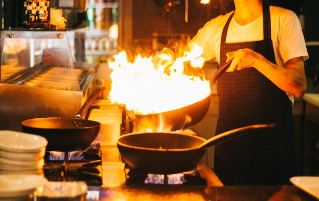 Foto sección media del chef preparando comida en la cocina de un restaurante