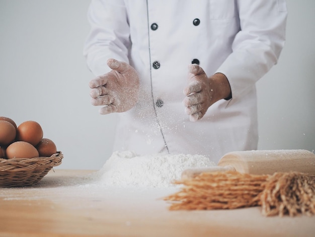 Sección media del chef preparando comida en la mesa contra un fondo blanco