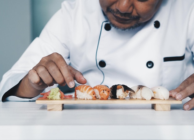 Sección media del chef preparando sushi en la tabla de cortar