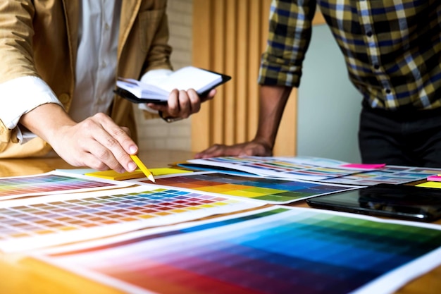 Sección media de colegas eligiendo una muestra de color en el escritorio de la oficina