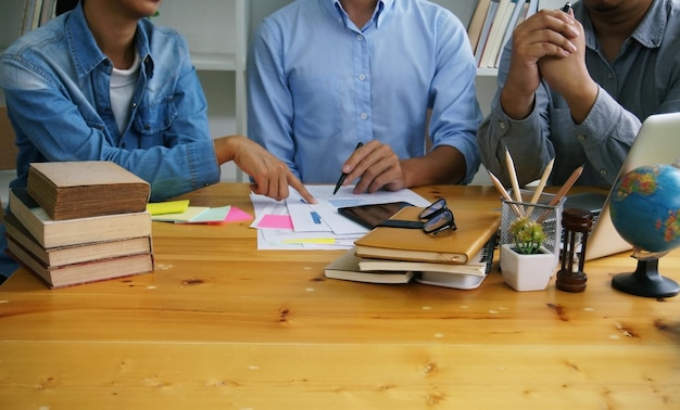 Foto sección media de colegas trabajando en el gráfico en el escritorio de la oficina