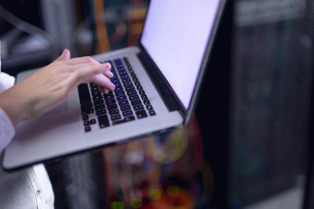 Sección media de una computadora portátil de mujer en la sala de servidores de computadoras. concepto de gestión y mantenimiento del servidor de bases de datos