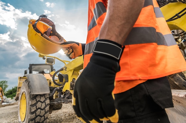 Foto sección media del conductor que sostiene el casco duro de las máquinas de construcción