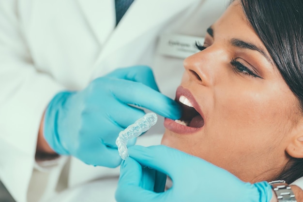 Sección media del dentista que sostiene las prótesis dentales mientras examina la boca del paciente