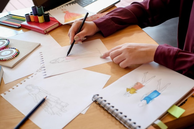 Sección media de un diseñador de moda haciendo un boceto en el estudio
