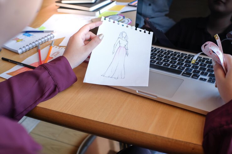 Foto sección media del diseñador de moda sosteniendo un boceto en el estudio
