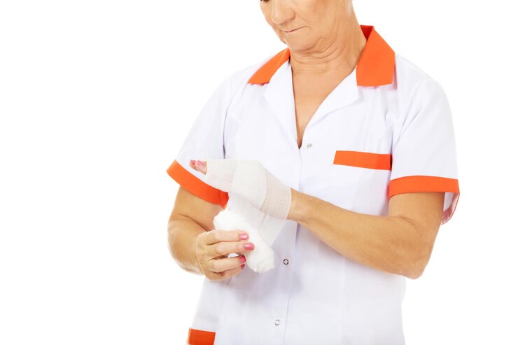 Foto sección media de una doctora aplicando vendaje en la mano contra un fondo blanco