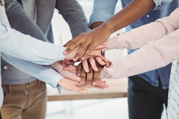 Sección media del equipo de negocios juntando sus manos