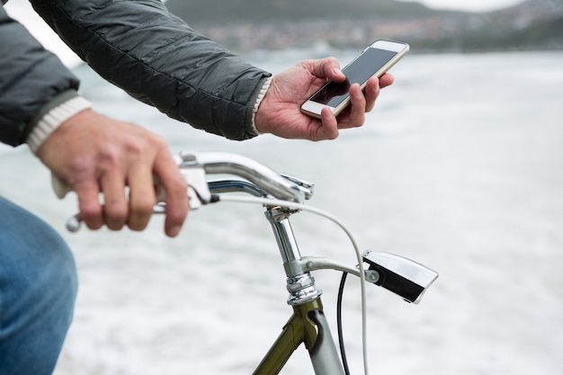 Sección media del hombre en bicicleta con teléfono móvil