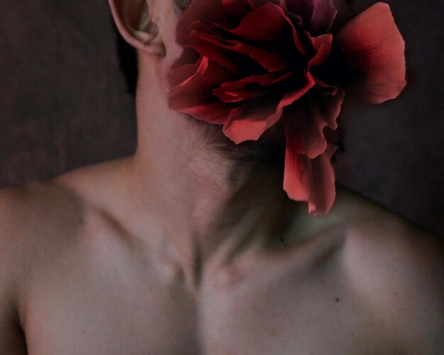 Foto sección media de un hombre sin camisa con una flor artificial