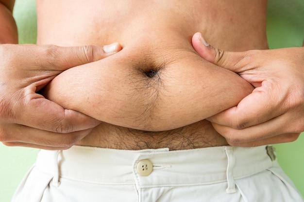 Sección media de un hombre sin camisa sosteniendo el abdomen
