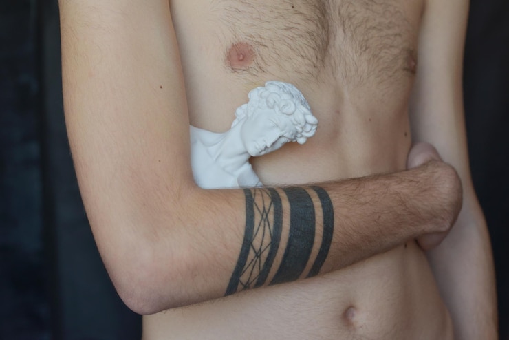 Foto sección media de un hombre sin camisa sosteniendo un busto masculino en casa