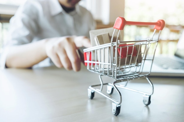 Sección media de un hombre con un carrito de compras en la mesa