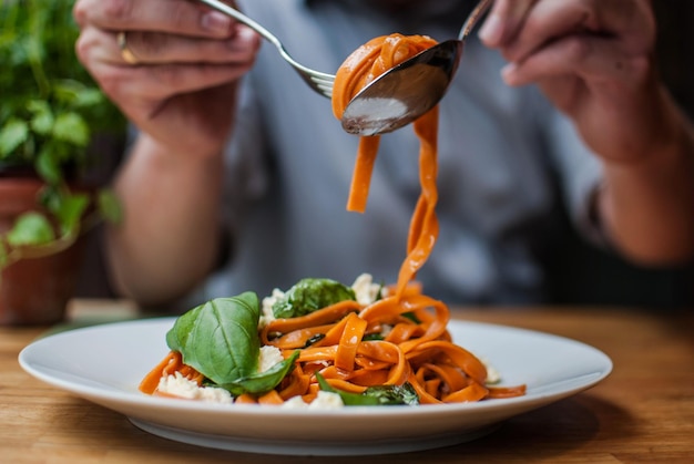 Sección media de un hombre comiendo pasta en un restaurante