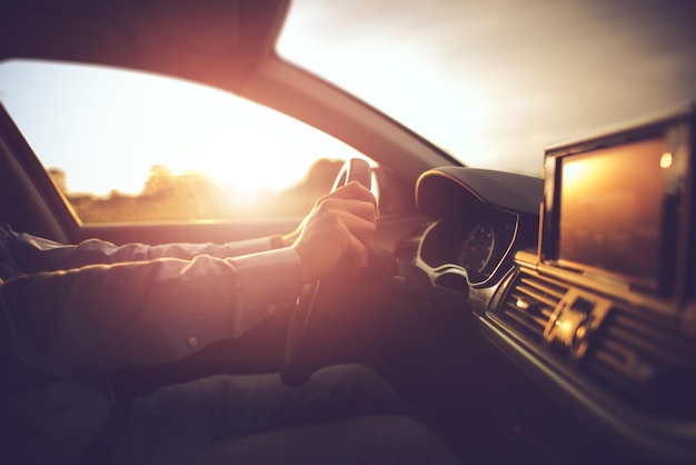 Foto sección media de un hombre conduciendo un coche durante la puesta de sol.