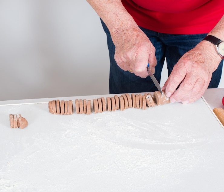 Foto sección media de un hombre cortando galletas en la mesa