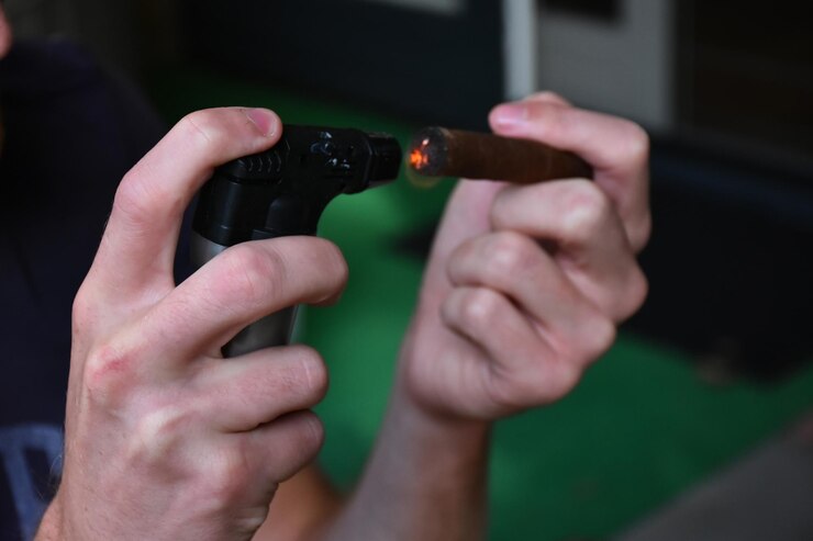 Foto sección media de un hombre encendiendo un cigarro en el interior
