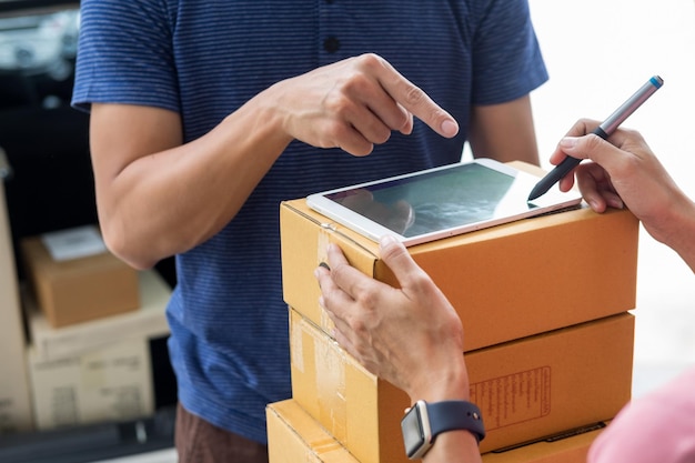 Foto sección media del hombre de la entrega señalando mientras la mujer firma en la tableta digital