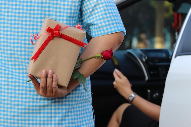 Foto sección media de un hombre escondiendo un regalo de una mujer