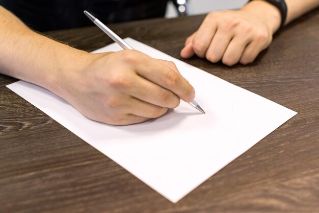 Foto sección media de un hombre escribiendo en papel en blanco en la mesa