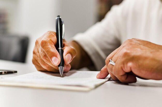 Foto sección media de un hombre escribiendo en papel en la mesa