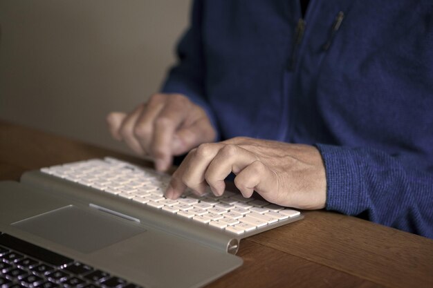 Sección media de un hombre escribiendo en el teclado en la mesa