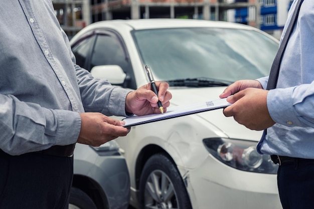 Sección media de un hombre firmando un papel con un hombre de negocios en un coche