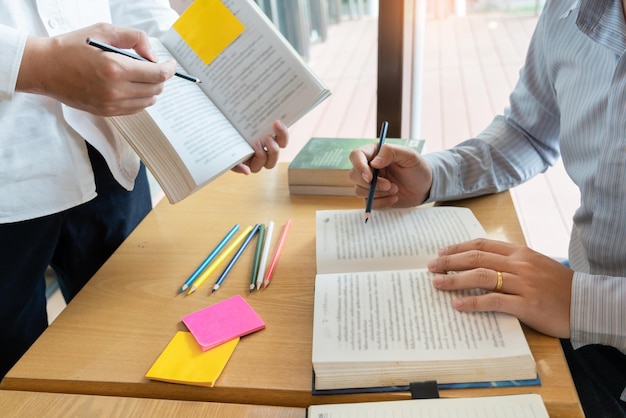 Sección media de un hombre y una mujer discutiendo mientras leen un libro en la mesa