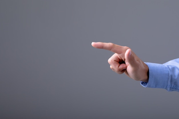 Sección media del hombre de negocios caucásico apuntando con el dedo, aislado sobre fondo gris. concepto de tecnología empresarial, comunicación y crecimiento.