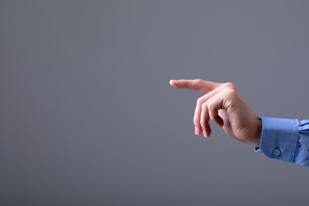 Sección media del hombre de negocios caucásico apuntando con el dedo, aislado sobre fondo gris. concepto de tecnología empresarial, comunicación y crecimiento.