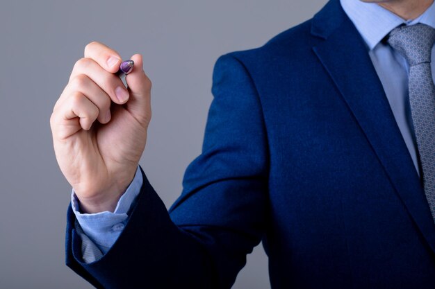 Foto sección media del hombre de negocios caucásico sosteniendo la pluma, aislado sobre fondo gris. concepto de tecnología empresarial, comunicación y crecimiento.