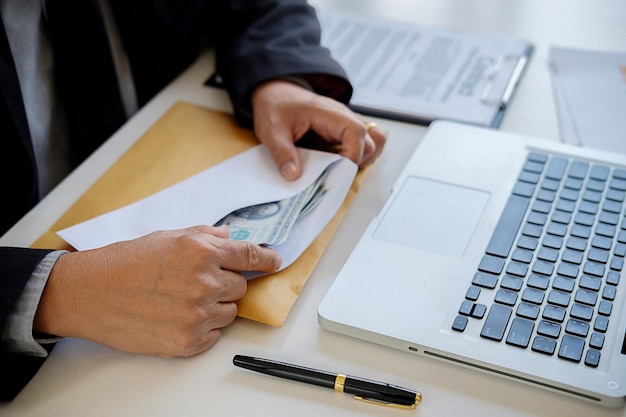 Sección media de un hombre de negocios con dinero en un sobre en la oficina