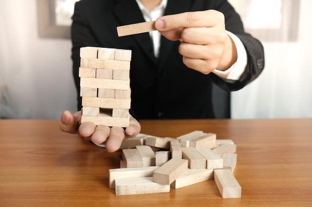Sección media de un hombre de negocios jugando a un juego de eliminación de bloques en el escritorio de la oficina