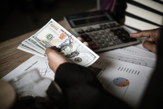 Foto sección media de un hombre de negocios sosteniendo papel moneda en la mesa