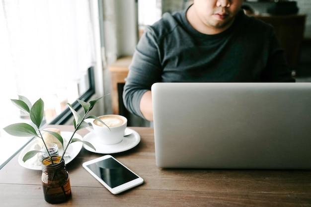 Sección media de un hombre de negocios usando una computadora portátil en una mesa en una cafetería