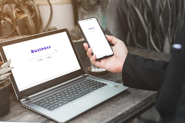 Sección media de un hombre de negocios usando una computadora portátil y un teléfono móvil