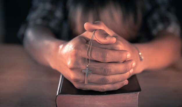 Foto sección media de un hombre orando en la biblia con velas encendidas en la mesa