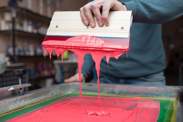 Sección media de un hombre con pintura en maquinaria en una fábrica