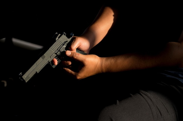 Foto sección media de un hombre con una pistola mientras está sentado en una silla en la habitación