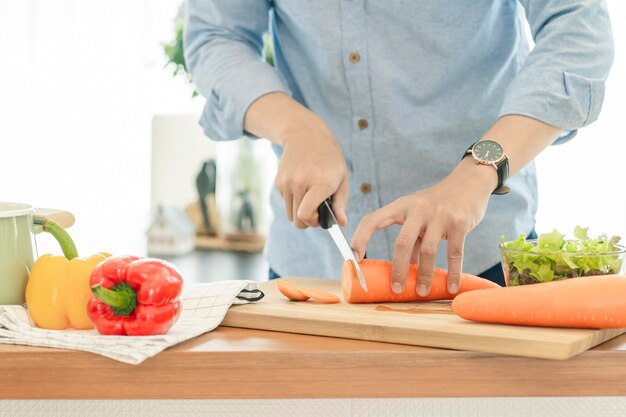 Sección media de un hombre preparando comida en la cocina de su casa