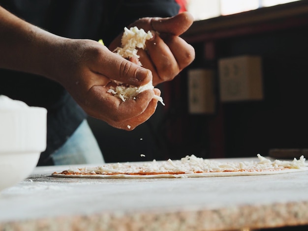 Foto sección media de un hombre preparando pizza en la mesa en casa