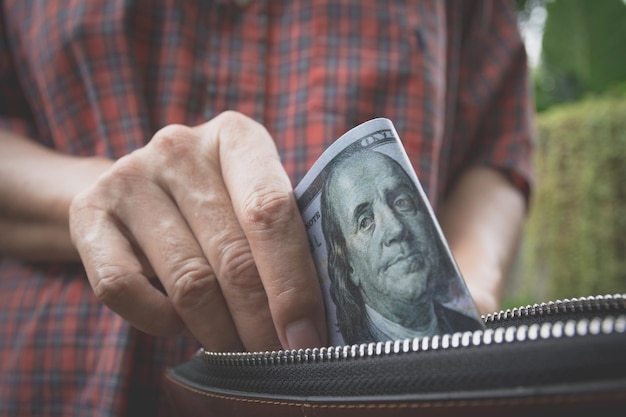 Foto sección media de un hombre quitando papel moneda de su bolso