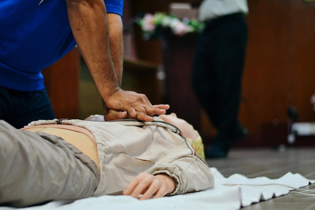 Sección media de un hombre realizando RCP en un maniquí